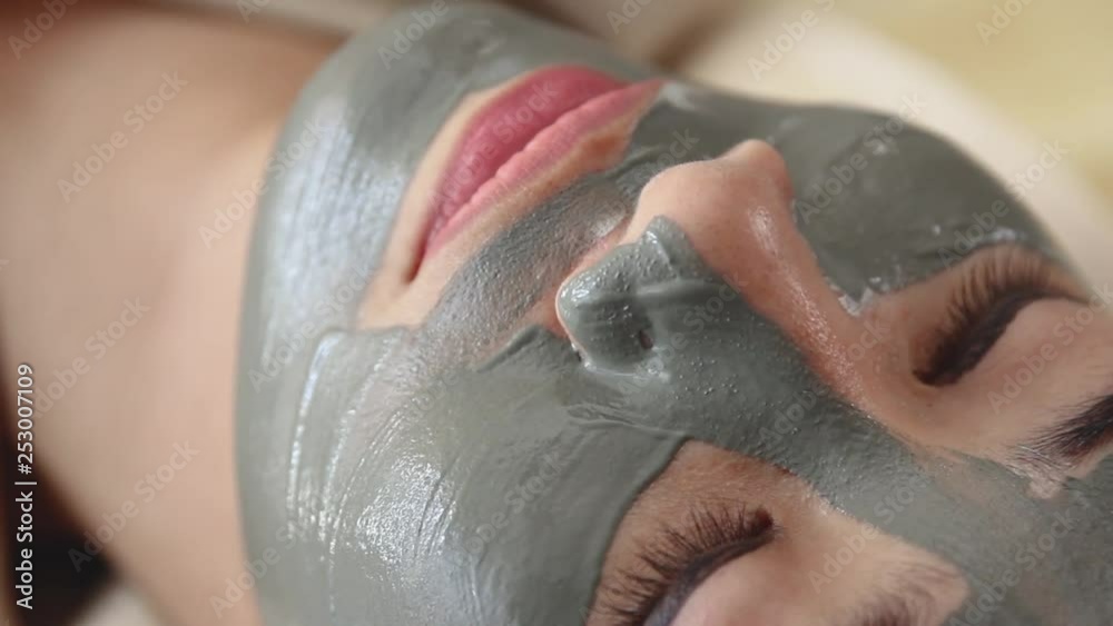 Young woman getting mask on her face in beauty salon clinic