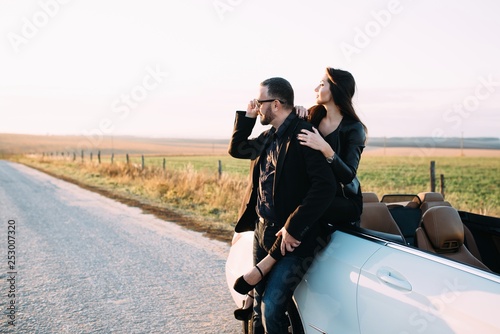 Sympathetic couple husband and wife spend time outside the city, sitting on a car hood © nazariykarkhut