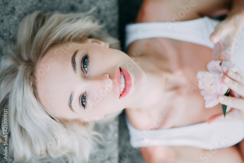 Blonde girl is lying on the grey background