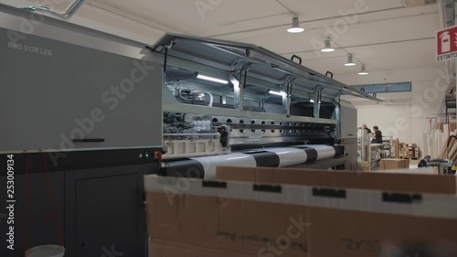 Details of a moving print head. Massive machinery. Professional  printing facility, big vinyl rolls, ready for export. Glossy, matte, ecological materials used for commercial billboards and press.