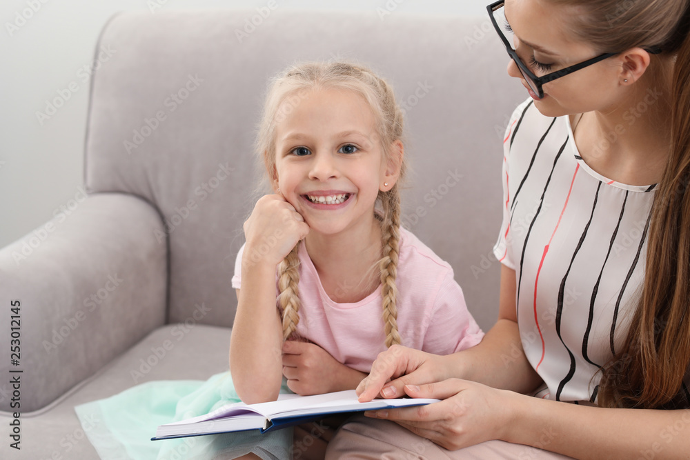 Little girl with speech therapist reading book in office Little girl with speech therapist reading book in office