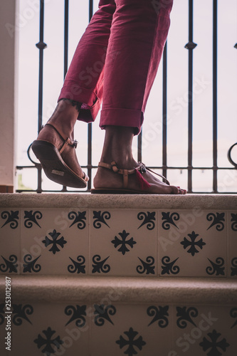 British Indian woman - feet in ethnic footwear with cymbals and tassel - climbing stairs in cropped trousers.  photo