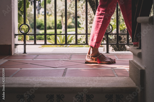 British Indian woman - feet in ethnic footwear with cymbals and tassel - climbing stairs in cropped trousers.  photo