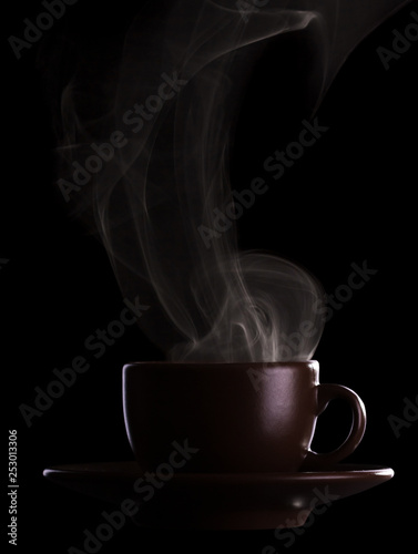 Silhouette coffee cups with saucer and hot steam isolated on black