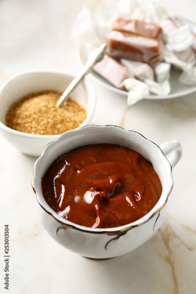 Cup with tasty melted caramel on table Cup with tasty melted caramel on table