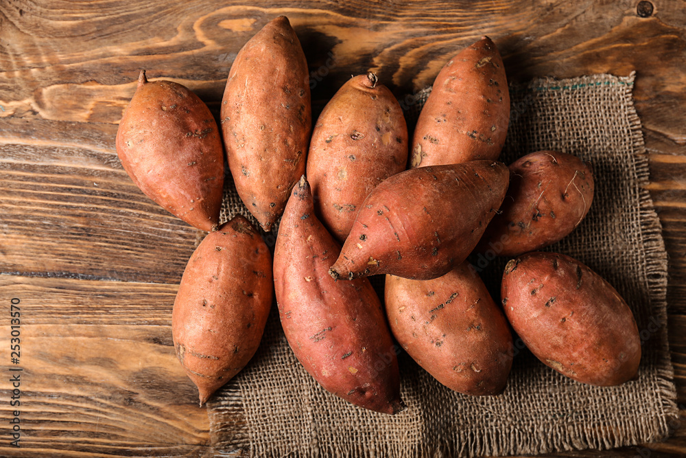 Raw sweet potato on wooden background Raw sweet potato on wooden background