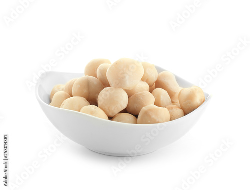 Bowl with peeled macadamia nuts on white background