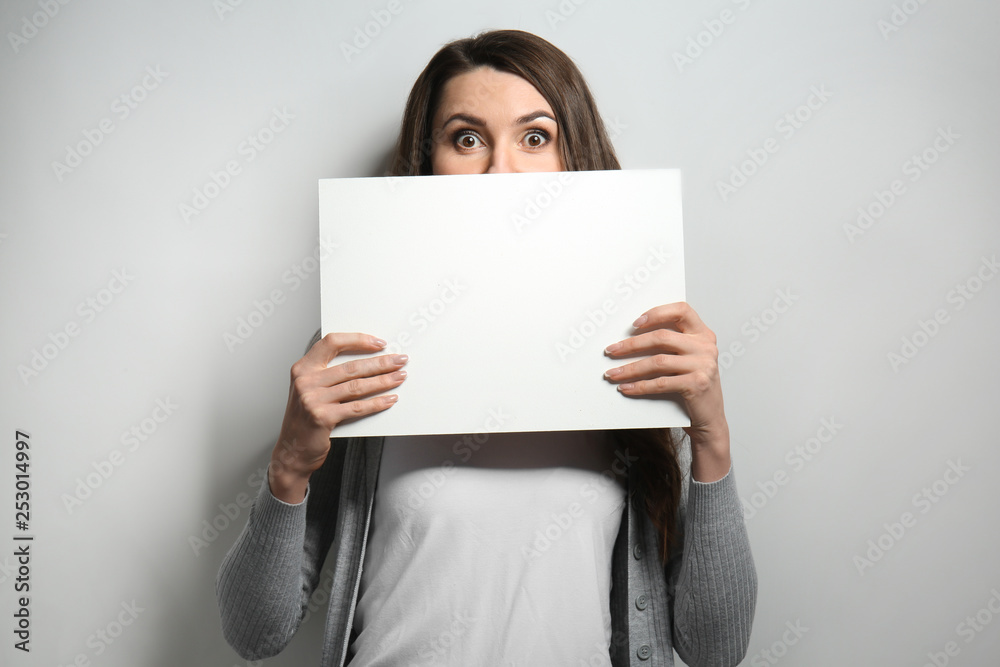 Portrait of beautiful woman with blank poster on light background Portrait of beautiful woman with blank poster on light background