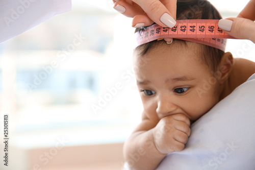 Pediatrician examining African-American baby in clinic photo