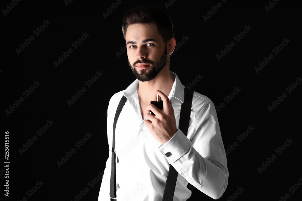 Handsome man with bottle of perfume on dark background Handsome man with bottle of perfume on dark background