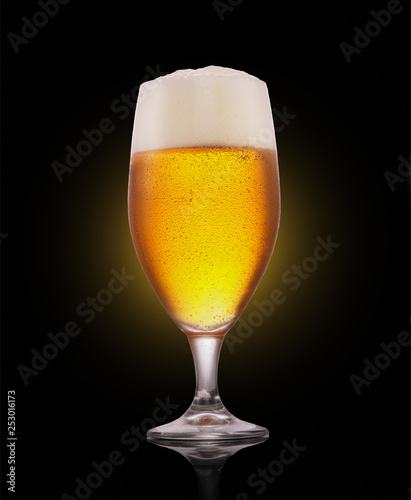 Glass of beer with foam on a dark background .