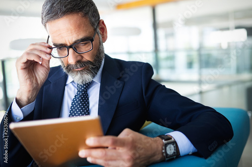 Business, technology and people concept - senior businessman with tablet pc working in office