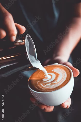 Fototapeta na wymiar vintage tone of some people pour milk to making latte art coffee at cafe or coffe shop