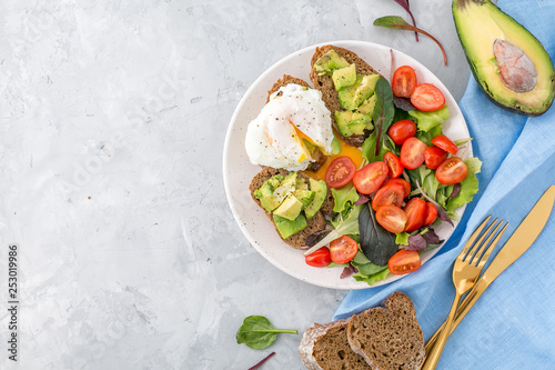Healthy Breakfast with avocado toasts, poached egg and salad