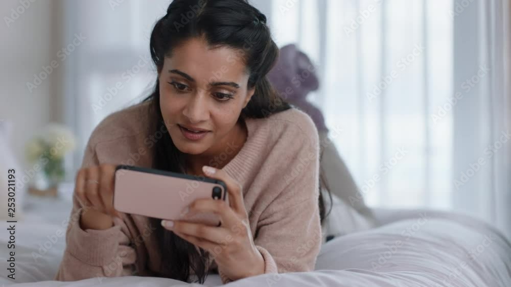 beautiful woman using smartphone browsing online watching entertainment enjoying mobile phone checking social media messages lying on bed at home beautiful woman using smartphone browsing online watching entertainment enjoying mobile phone checking social media messages lying on bed at home