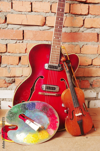 Art palette, electric guitar and violin on a brick wall background © yrafoto