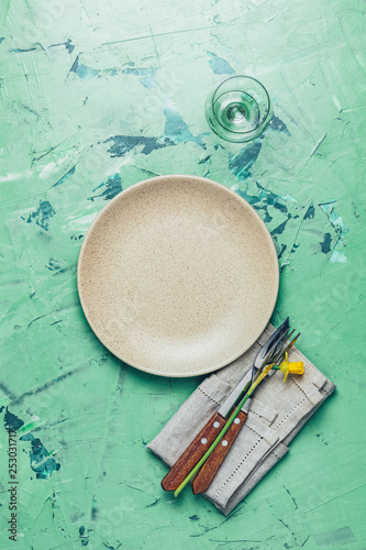 Empty beige plate and cutlery with daffodils on a napkin