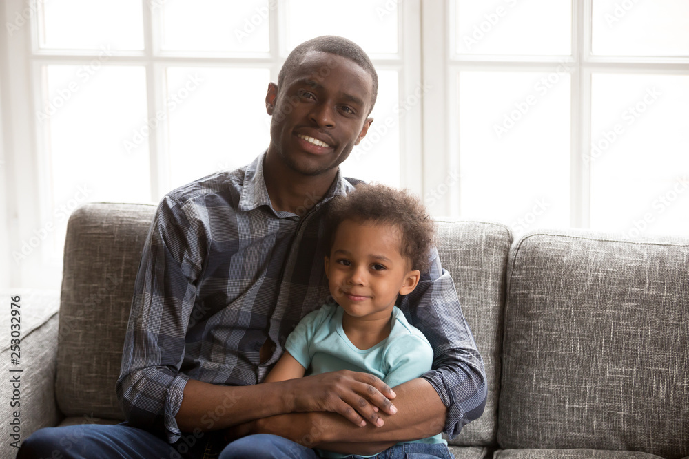 Portrait of happy dad and small kid hug on couch Portrait of happy dad and small kid hug on couch