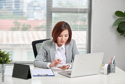 Asian businesswoman or accountant working pointing graph discussion and analysis data charts and graphs and using a calculator to calculate numbers. Business finances and accounting concept
