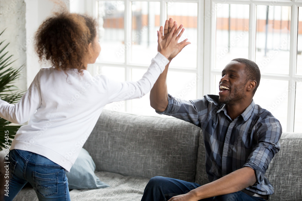 Excited mixed race daughter give high five to young dad Excited mixed race daughter give high five to young dad
