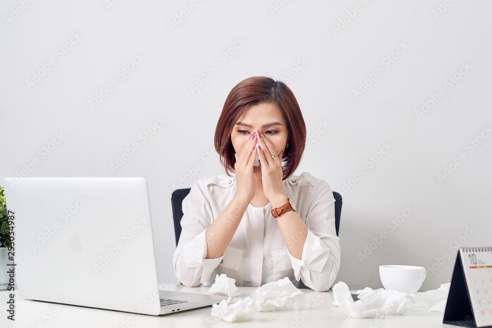 Sad exhausted woman with tissue suffering from cold while working with laptop at table Sad exhausted woman with tissue suffering from cold while working with laptop at table