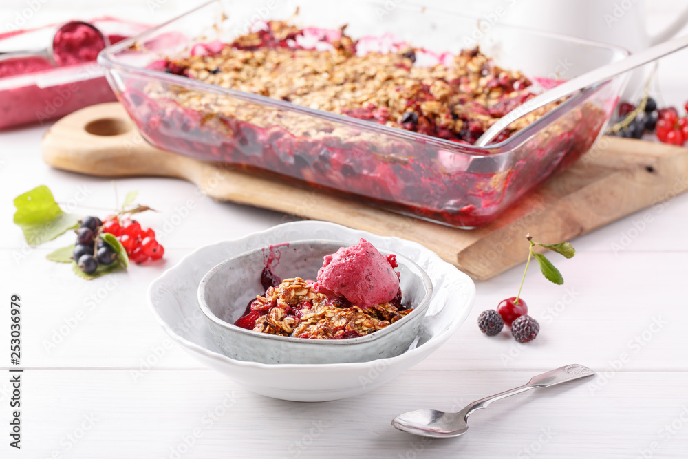 Apple and berry crumble with oats served with fruit ice-creame on white table. Crispy fruit pie, healthy summer dessert. Close-up. Apple and berry crumble with oats served with fruit ice-creame on white table. Crispy fruit pie, healthy summer dessert. Close-up.