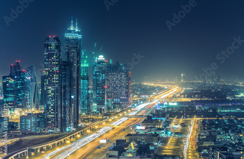 Colourful nightime skyline of Dubai, United Arab Emirates. Aerial view on highways and skyscrapers.