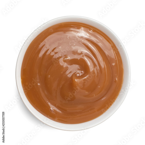 Sweet caramel sauce in bowl isolated on white background. Top view