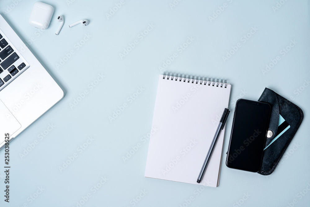 Flat lay of composition with laptop, phone, wireless headphones, notepad, wallet, credit card on light blue background with copy space for text. Flat lay of composition with laptop, phone, wireless headphones, notepad, wallet, credit card on light blue background with copy space for text.