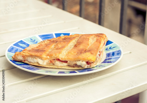 Fried calzone pizza with ham, mozzarella, tomatoes from bakery shop of Catania, Sicily, Italy.