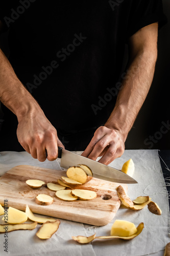 Cooking potato chips. Chef slicing fresh potato. Healthy food.