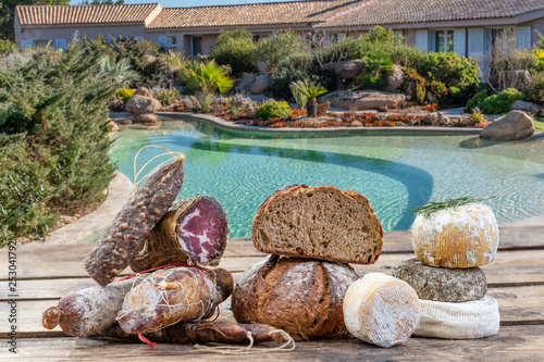 Corsican specialities appetizer: delicatessen, and cheese made in Corsica over a swimming pool panorama background, photo