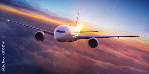 Commercial airplane jetliner flying above dramatic clouds in beautiful sunset light. Travel concept. photo