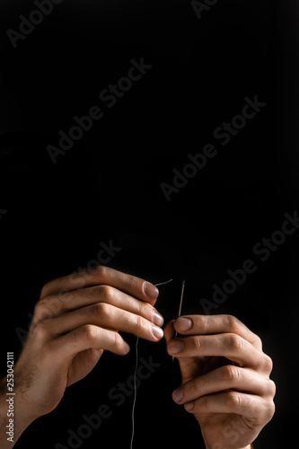 Man tailor threading a needle