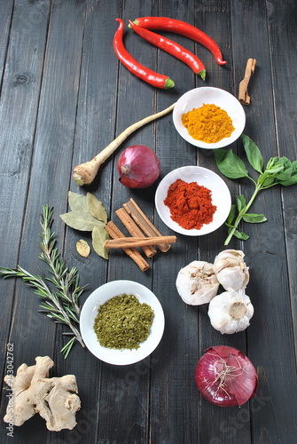 Colorful various of fresh and dried herbs, spices for cooking. Spice and herb seasoning, paprika powder, cinnamon, red onion. garlic, basil, ginger root on dark background
