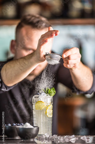 Professional barman making alcoholic cocktail drink with fruits sugar and herbs