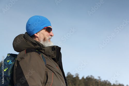 Male traveler with a beard in a blue hat and sunglasses against the blue sky © Nataliia Makarova