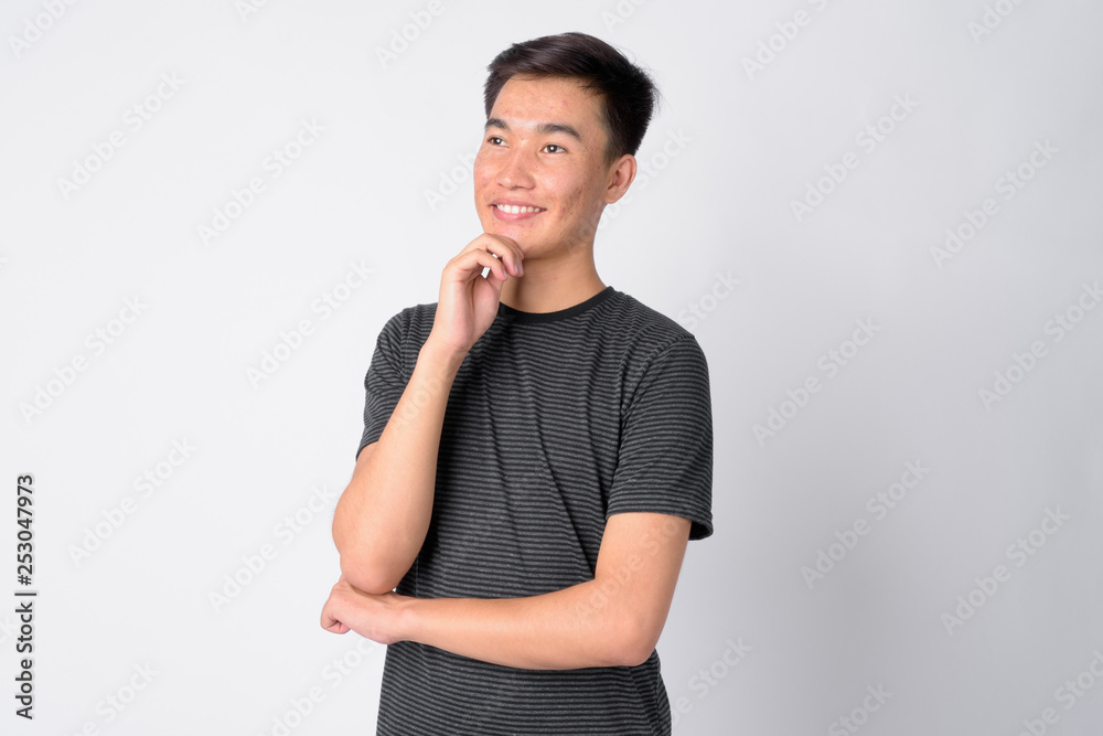 Portrait of young happy Asian man thinking Portrait of young happy Asian man thinking
