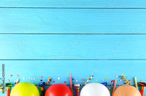 Minimal style composition with different pastel color air balloons with streamer ribbons and other chilldren birthday party attributes on bright background. Top view, close up, flat lay, copy space.