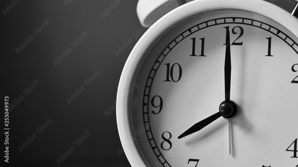 Closeup face of white analog bell clock. Black and white background. Number on clock face. Closeup face of white analog bell clock. Black and white background. Number on clock face.