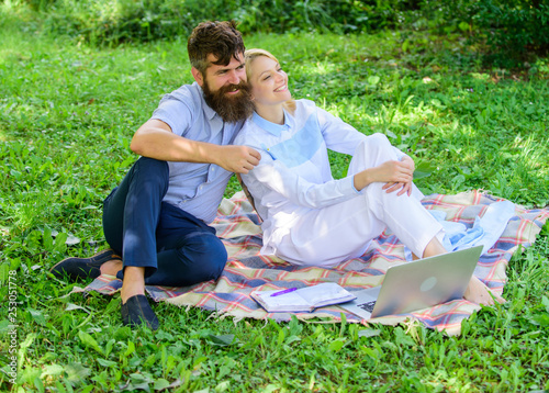 Couple bearded man and blonde woman relax nature while sit on green grass meadow. Relax and inspiration concept. Family enjoy relax nature background. Couple with laptop relax natural environment