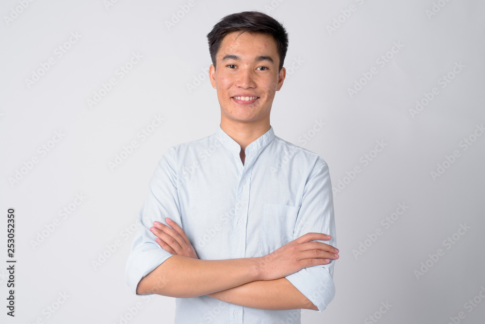 Portrait of young happy Asian businessman smiling with arms crossed Portrait of young happy Asian businessman smiling with arms crossed