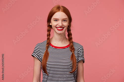 Konstfotografi Nice pretty red-haired girl with red lips, two braids, chrarming smile, shows wh