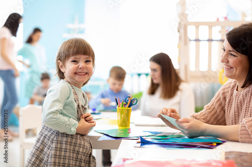 kids learning arts and crafts in kindergarten with teacher photo