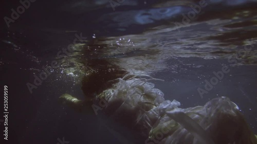 Girl in a white dress with ribbons under the water