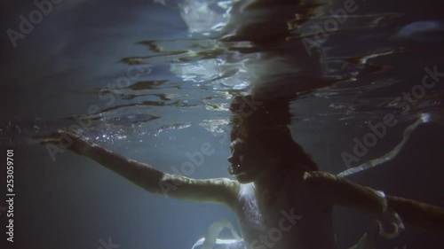 Girl in a white dress with ribbons under the water