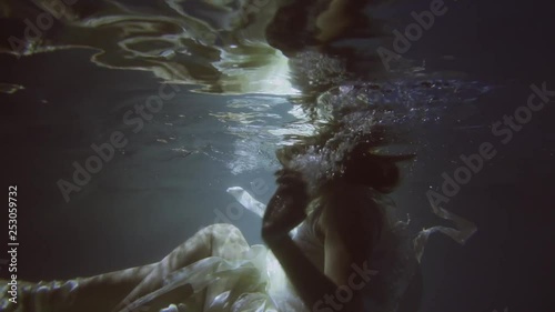 Girl in a white dress with ribbons under the water