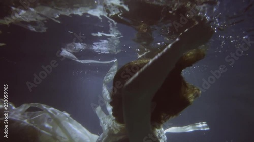 Girl in a white dress with ribbons under the water