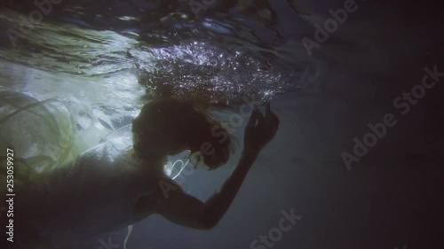 Girl in a white dress with ribbons under the water