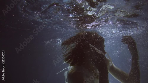 Girl in a white dress with ribbons under the water